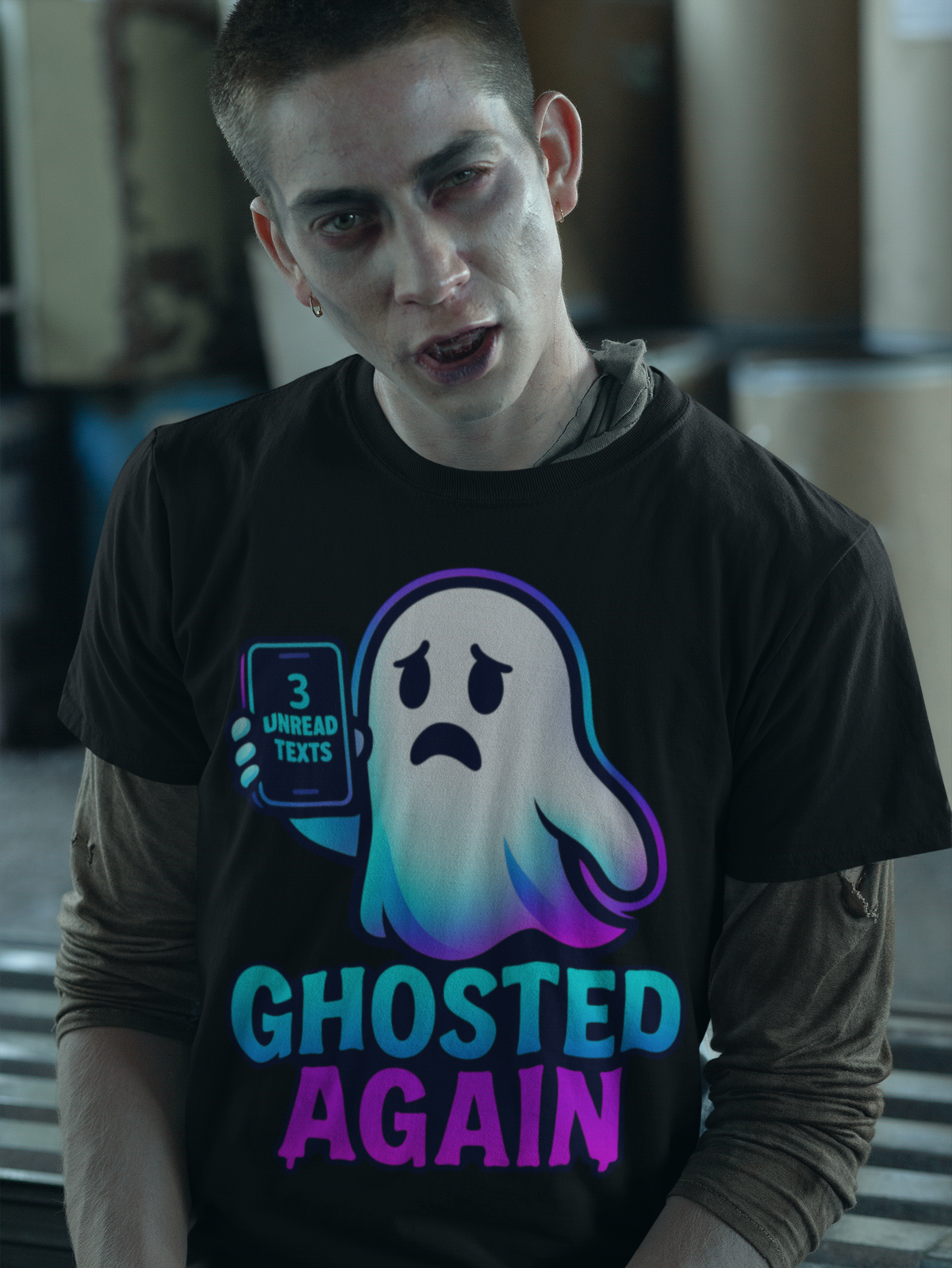 A man wearing a black graphic t-shirt with a cartoon ghost holding a phone that says '3 UNREAD TEXTS' and the text 'GHOSTED AGAIN' in blue and purple, layered over a brown long-sleeve shirt.