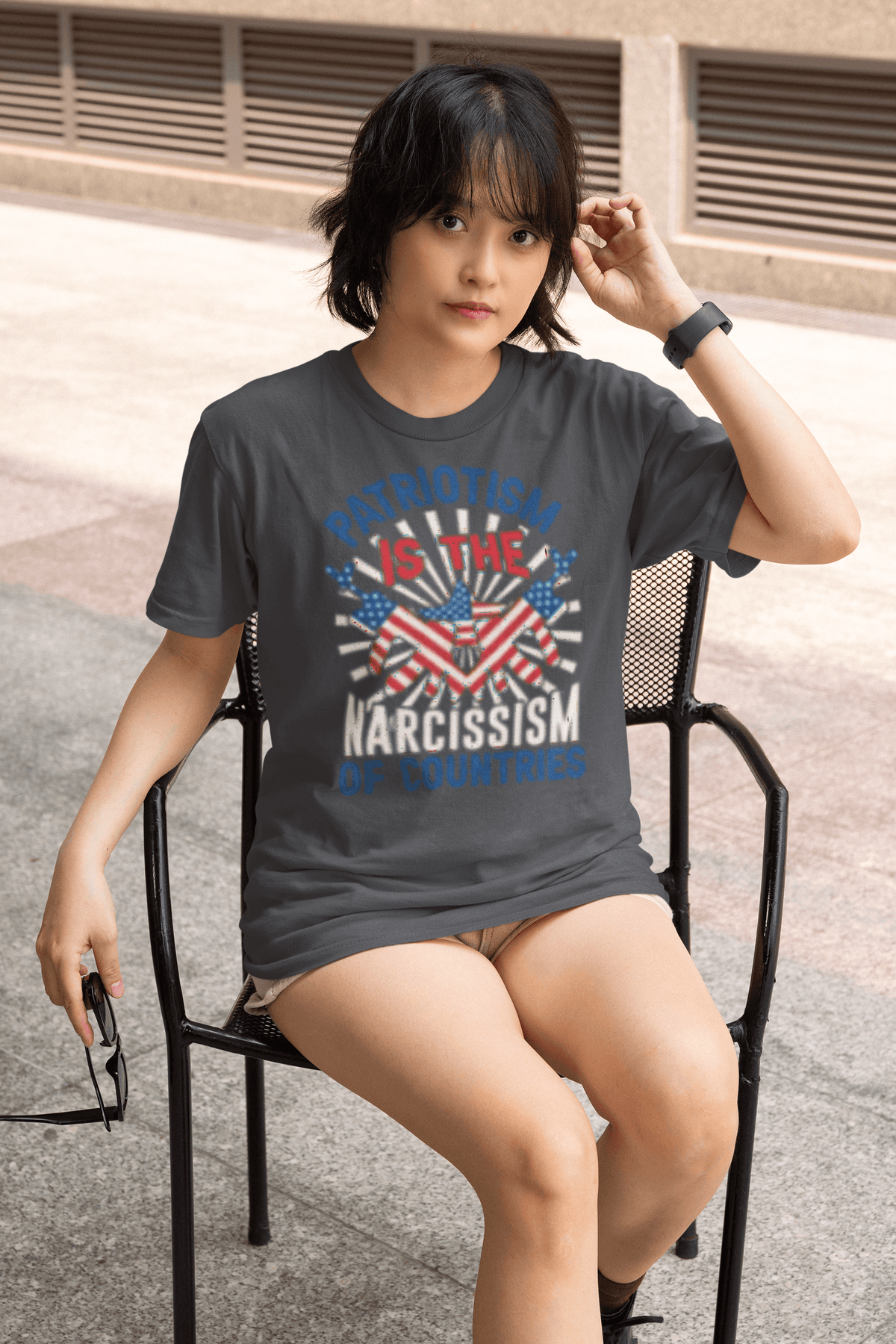 Narcissism of Countries anti-establishment graphic t-shirt worn by serious woman sitting chair