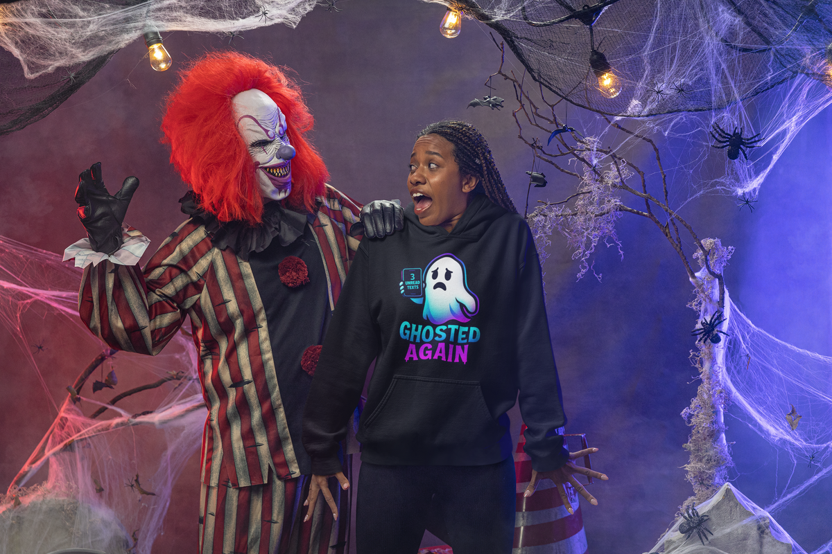 A person wearing a black hoodie with a 'GHOSTED AGAIN' graphic stands next to a person in a scary clown costume in a Halloween-themed decorated indoor setting with cobwebs and string lights.