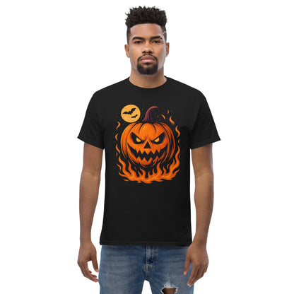 A man wearing a black short-sleeve t-shirt with a graphic of a jack-o'-lantern pumpkin surrounded by orange flames and a small flying bat in a yellow moon, paired with blue jeans, against a plain white background.