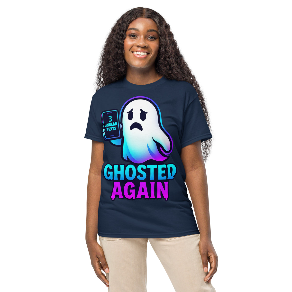 A woman modeling a navy blue graphic t-shirt with a cartoon ghost and the text 'GHOSTED AGAIN' in neon blue and pink, paired with beige pants, against a plain white background.